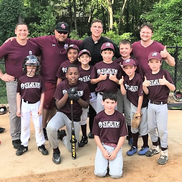 U10 Baseball team poses for a picture with priest