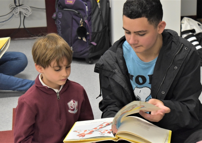 an 8th grade student reads to his kindergarten buddy