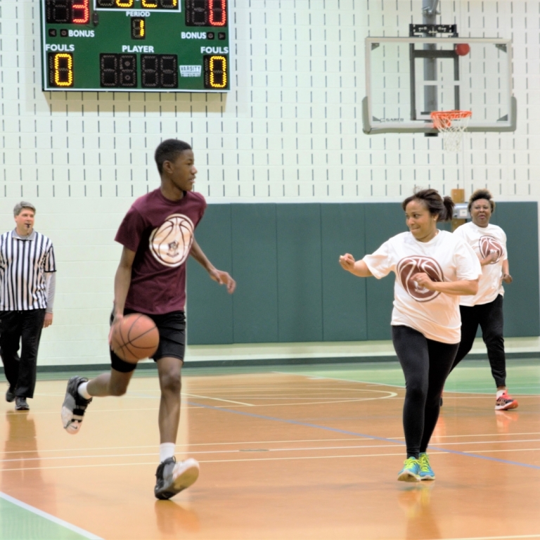 Eighth grade boys goes up against a parent during the 8th grade versus parents and faculty basketball game