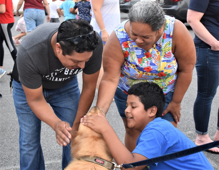 Parents pet a dog with their child during the Back To School Picnic