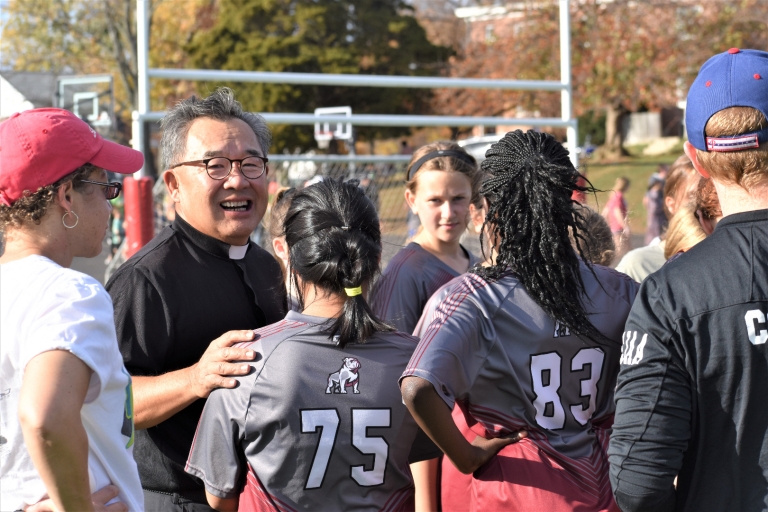 Girls pray with Father Lee before a soccer game