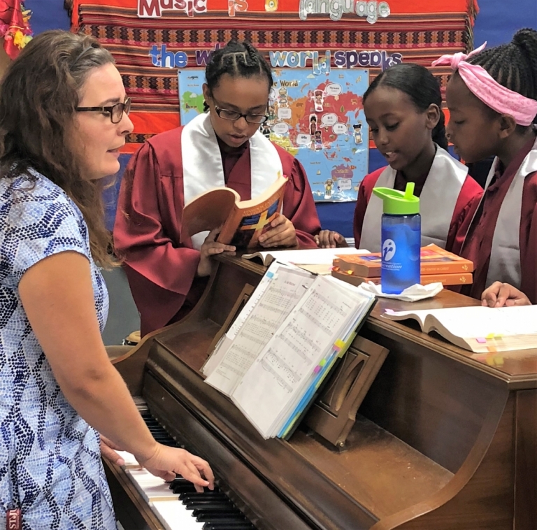 Mrs. White plays piano while preparing students to sing for Mass