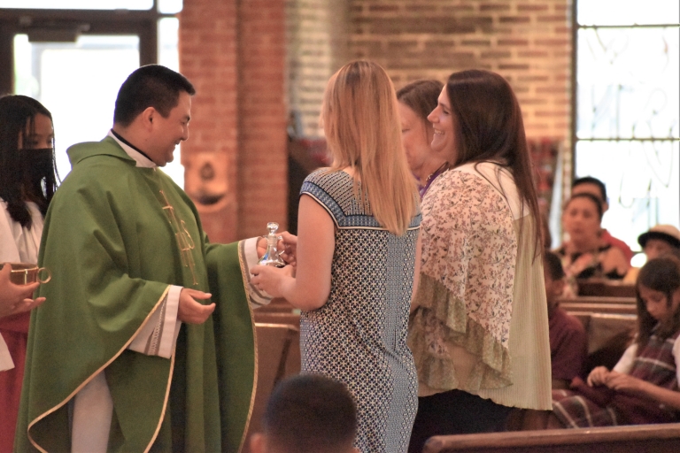 Three teachers bring the gifts of bread and wine to the altar