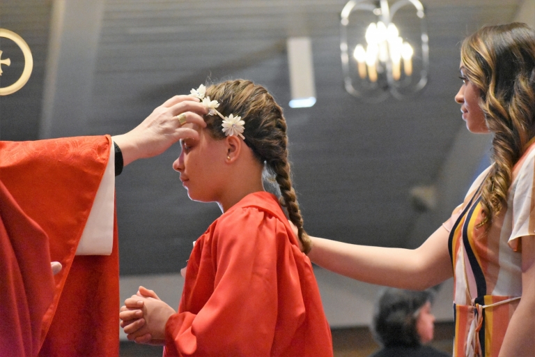 A seventh grade girl receives the gift of the Holy Spirit at confirmation